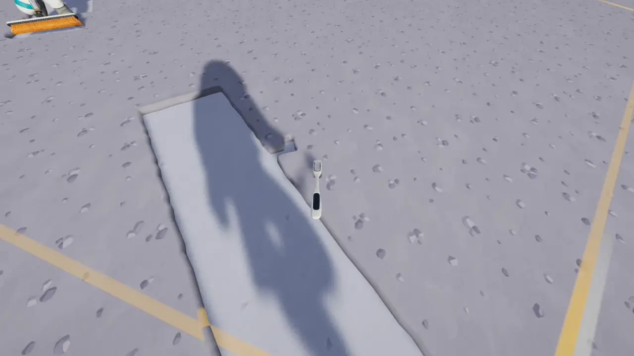 First-person view of a toothbrush-sized hand tool beside a narrow strip of freshly cleaned lunar ground